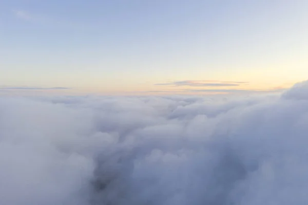 Aerial view White clouds in blue sky. Top fly. Looking from the drone. Aerial bird\'s eye view. Aerial top view cloudscape. Texture of clouds. View from above. Sunrise or sunset over clouds
