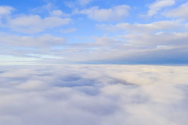 Aerial view White clouds in blue sky with solar halo. Top view. View from drone. Aerial bird\'s eye view. Aerial top view cloudscape. Texture of clouds. View from above. Sunrise or sunset over clouds