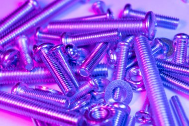 Arka planda metal cıvatalar ve fındıklar. Krom vida cıvatalar ve fındıklar mavi ve pembe tonlarda. Çelik cıvatalar ve fındık desenleri. Fındık ve cıvata seti. İş için araçlar.