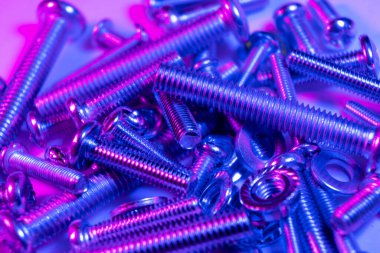 Arka planda metal cıvatalar ve fındıklar. Krom vida cıvatalar ve fındıklar mavi ve pembe tonlarda. Çelik cıvatalar ve fındık desenleri. Fındık ve cıvata seti. İş için araçlar.