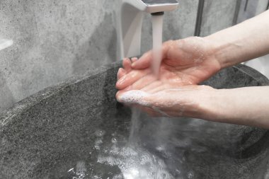 Coronavirus salgını önleme. Sabun ve sıcak suyla ellerini yıkamak. Tırnak ovalamak ve parmaklar. Kadın akan suyun altında elini yıkıyor..