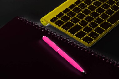 Soyut iş yeri. Kablosuz bilgisayar klavyesi, not defteri ve kalem ofis masasında.