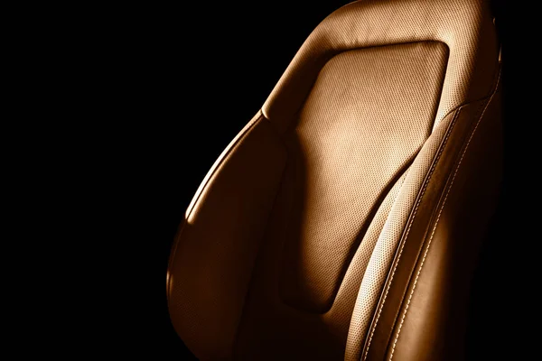 Brown leather interior of the luxury modern car. Perforated brown leather comfortable seats with stitching isolated on black background. Modern car interior details. Car detailing. Car inside