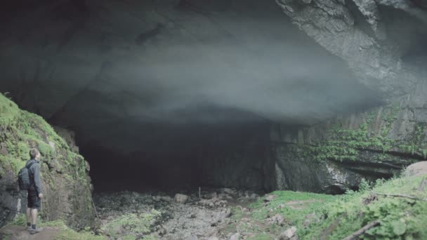Чоловік, що стоїть на вході в печеру, проміжок часу. Чарівний туман з печерного входу — стокове відео