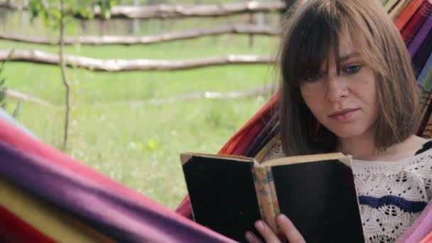 Meisje in hangmat lezen van een boek - middellange schot — Stockvideo