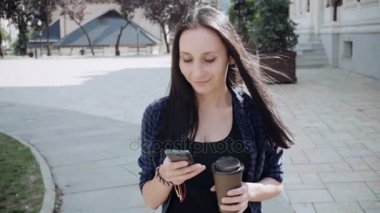 Genç kadınlar ile yürüyüş ve kahve içme smartphone. Orta atış 