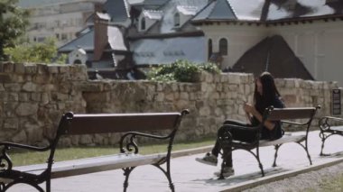 Akıllı telefon mesaj ile bankta oturmuş ve gülümseyen güzel genç kız