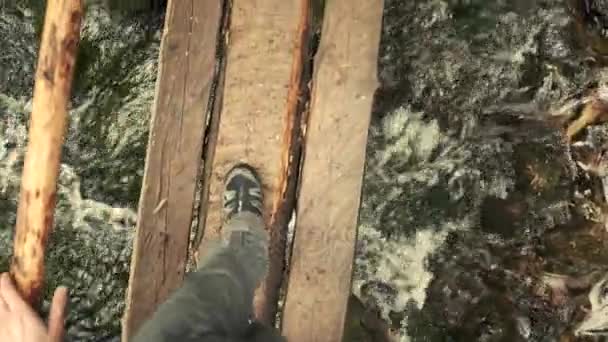 Muž, chůze na malý dřevěný most přes řeku v lese. Zpomalený pohyb, perspektivu pohledu — Stock video