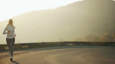 Güzel günbatımında yolda tek başına çalışan bir kadın. Sonbahar spor ve özgürlük kavramı. Dusk üzerinde eğitim atlet.