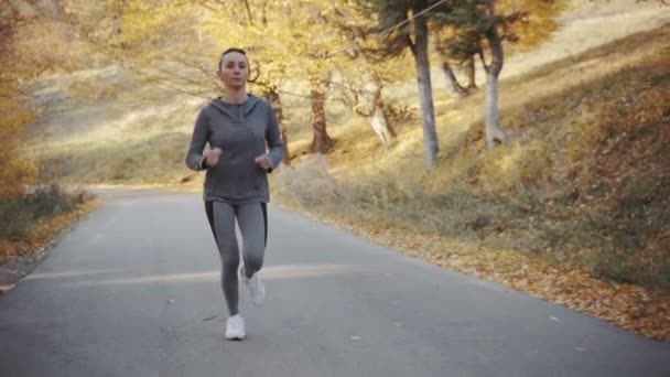 Жінка-спортсменка біжить по лісовій дорозі — стокове відео