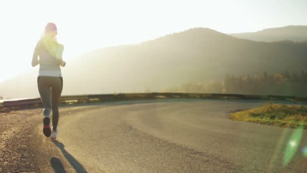 Frau läuft allein bei schönem Sonnenuntergang auf der Straße. Herbstsport und Freiheitskonzept. Athletentraining in der Dämmerung. — Stockvideo