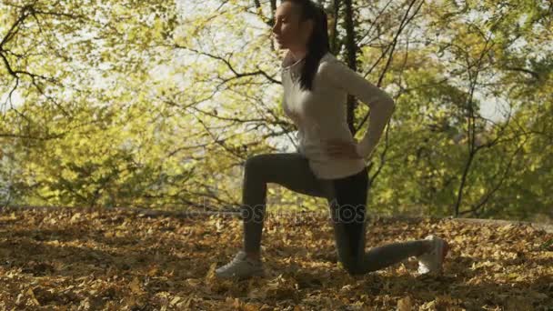 Entrenamiento de corredor al aire libre, concepto de estilo de vida saludable. Mujer atlética calentándose antes de su entrenamiento matutino en el bosque. Paisajes otoñales — Vídeo de stock