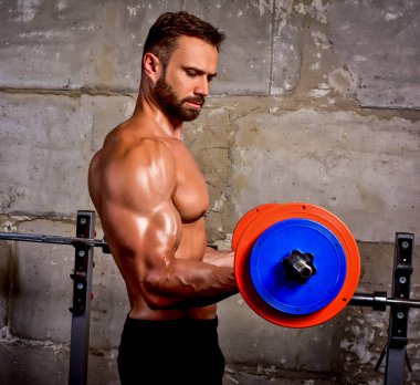 Halter pazısı egzersizi yapan sakallı kaslı bir adam.