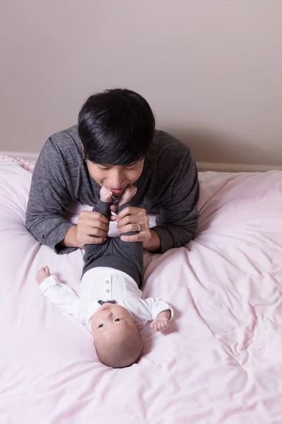 Father having fun with infant son feet while lying in bed — Stock Photo, Image