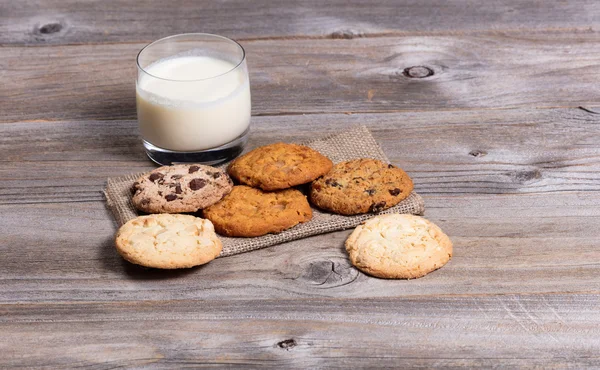 Variety of baked cookies on napkin and glass of milk — Stock Photo, Image