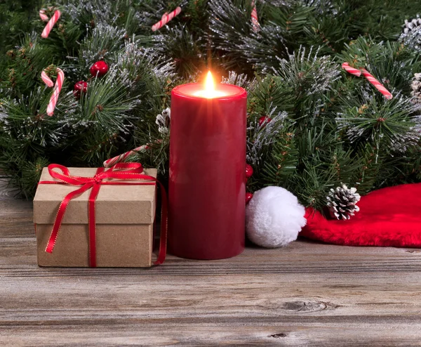 Glowing red candle surrounded by Christmas decoration on rustic — Stock Photo, Image