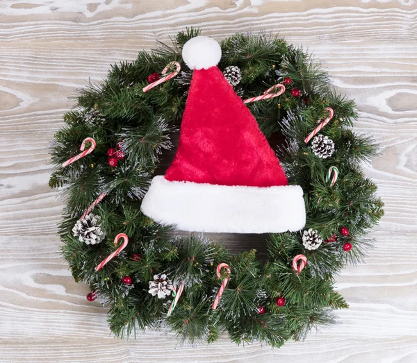 Noel çelenk ve Noel Baba şapkası ile ışık ve şekerler wh üzerinde — Stok fotoğraf