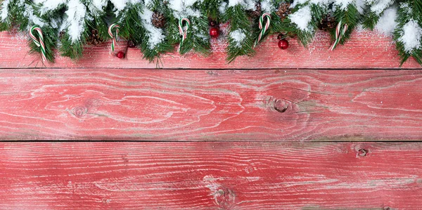 クリスマスの雪のモミの枝を持つ素朴な赤い木の板 — ストック写真