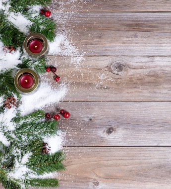Kar kaplı Noel çam dalları ve rustik ahşap mum