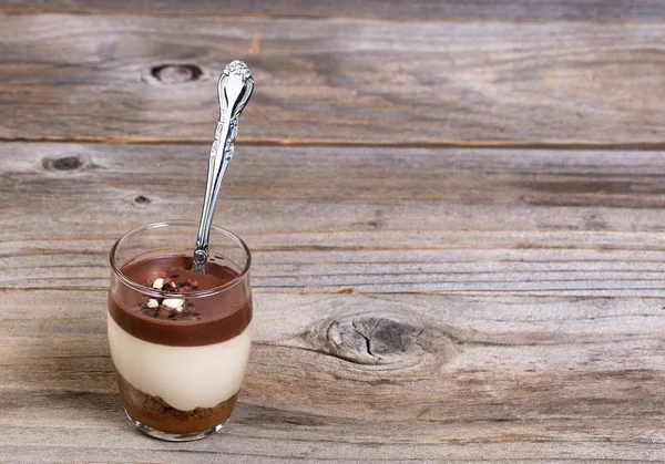 Schokoladenpudding und Kuchen in Tasse mit Löffel auf rustikalem Holz — Stockfoto