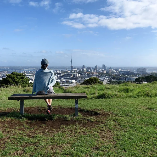 Woman sitting on bench will looking at skyline of Auckland — Stock Photo, Image