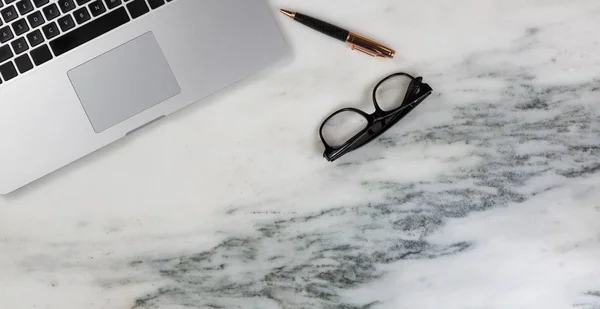 Configuración de escritorio de mármol con portátil con bolígrafo y gafas de lectura — Foto de Stock