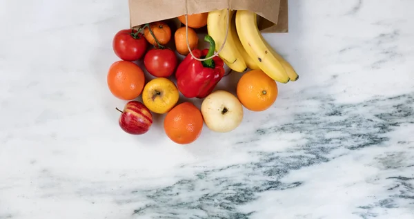 Fresh fruit and vegetables spilling out of a brown paper bag ont — Stock Photo, Image