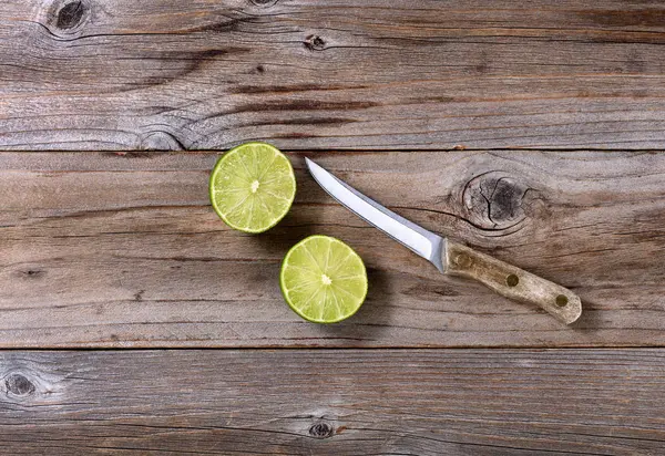 Sliced lime and paring knife on rustic wood in flat lay format — Stock Photo, Image