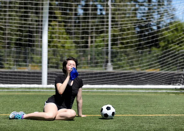 Adolescente chica bebiendo mucha agua durante un día caluroso en el fútbol — Foto de Stock