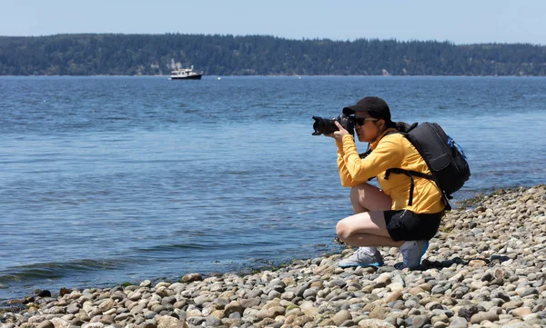 Woman nature photographer working on photos near shoreline of oc — Stock Photo, Image