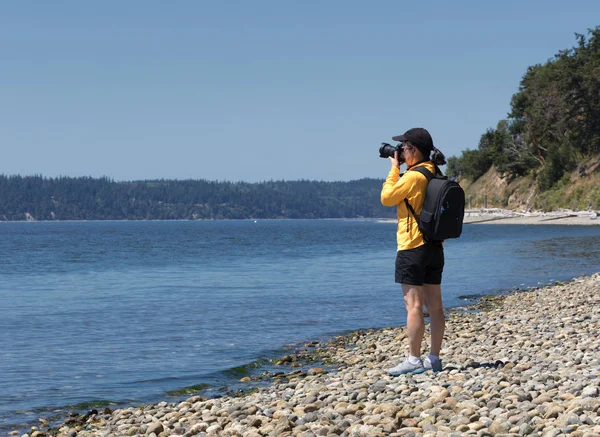 Женщина фотограф делает фотографии озера во время хорошего лета да — стоковое фото