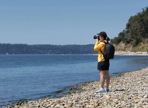 Mujer fotógrafa tomando fotos de un lago durante el verano da agradable — Foto de Stock