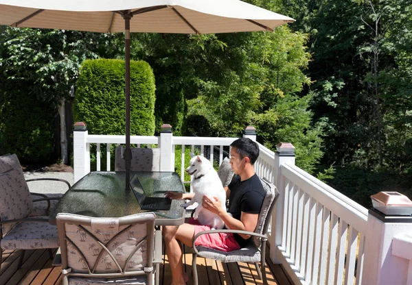 Young man and his pet dog working from home on his cedar home de — Stock Photo, Image