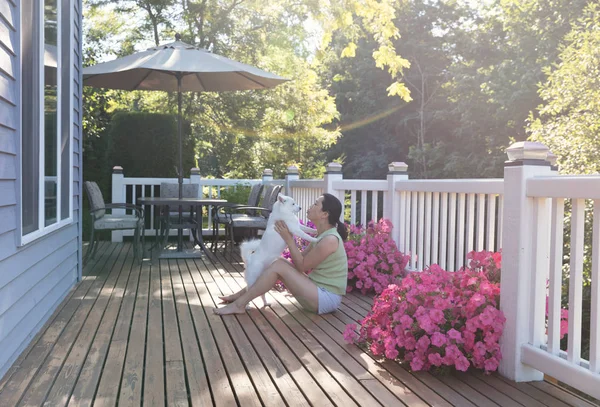 Жінка і її домашня собака на відкритому повітрі на домашній палубі під час яскравого сонячного світла — стокове фото