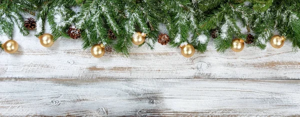 Рождественские ветви и золотые украшения со снегом на деревенском белке — стоковое фото