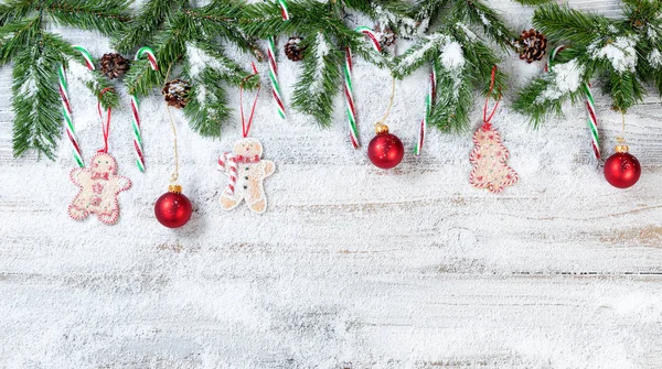 Branches de Noël enneigées avec ornements suspendus sur blanc rustique — Photo