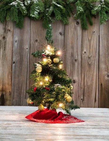 Dekorasi pohon Natal kecil pada kayu pedesaan dengan backgr bersalju — Stok Foto