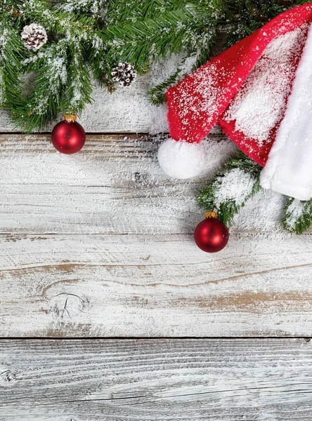 Χιονισμένο χριστουγεννιάτικο έλατο κλαδιά με παραδοσιακό καπέλο Santa και κοσμή — Φωτογραφία Αρχείου