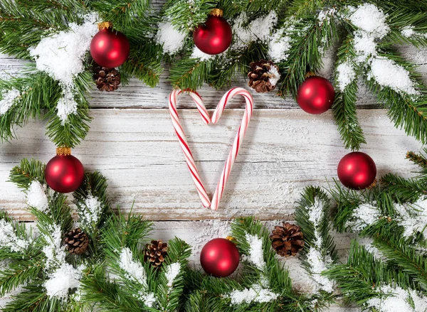 Ramas de árboles nevados de Navidad con bastones de caramelo formando corazón — Foto de Stock