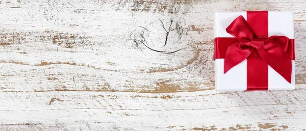 Scatola regalo con fiocco rosso su legno rustico in vista lay flat — Foto Stock