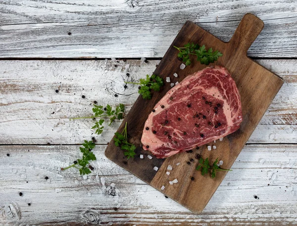 Raw slice of beef steak on old cutting board — Stock Photo, Image