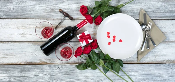 Valentine dinner with wine and roses on rustic wooden table