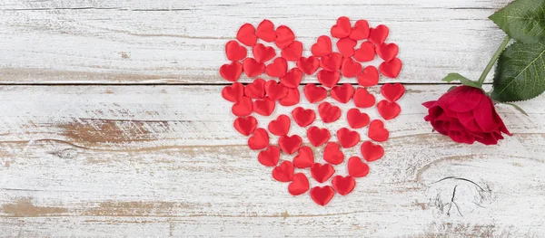 Filled red heart shapes and single rose on rustic white wood — Stock fotografie