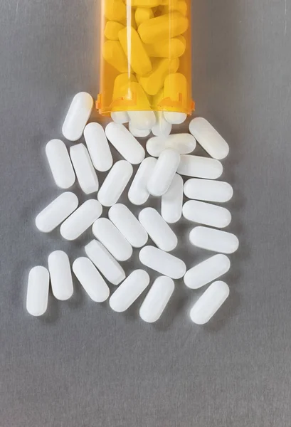 Tablet Opioid tumpah keluar dari botol ke meja baja tahan karat — Stok Foto