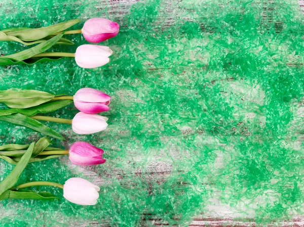Easter tulips on green grass and wooden background