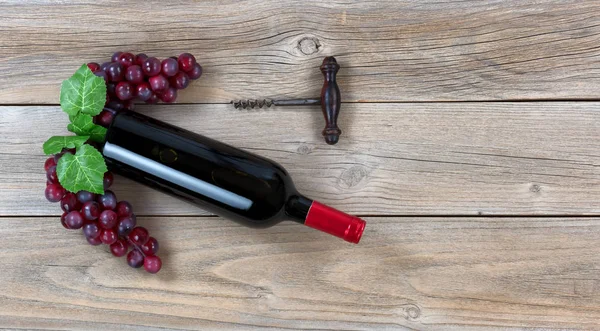 Bottiglia di vino rosso con uva e cavatappi su legno bo intemperie — Foto Stock