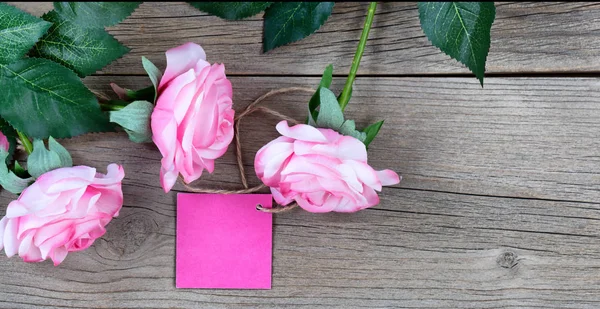 Preciosas rosas rosadas y etiqueta de regalo para las vacaciones del Día de las Madres en rústico —  Fotos de Stock