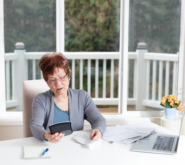 Senior vrouw weergeven van zorg tijdens het kijken naar haar berekeningen — Stockfoto