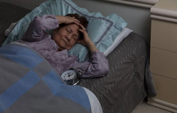 Starší žena s bolestí hlavy během noci v posteli — Stock fotografie