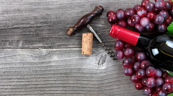 Donkere fles rode wijn en druiven op vintage houten planken — Stockfoto